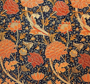 Design by William Morris for a furnishing fabric featuring flowers and leaves in oranges and browns on an inky background