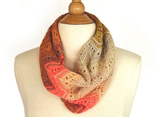 Load image into Gallery viewer, A multi coloured lace knitted cowl in shades of cream, coral and tan on the neck of a cream dress mannequin on a white background. Pattern is Adventurer Cowl by Ambah O'Brien
