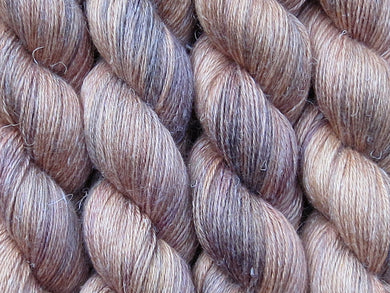 A close up of variegated tan with hints of orange, dark cocoa brown and maroon coloured skeins of non-superwash baby alpaca, silk and linen 4ply fingering weight yarn (Butterscotch on Spinifex)