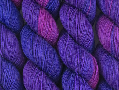 A close up of deep clear variegated magenta, plum, deep purple and violet coloured skeins of superwash merino and nylon 4ply fingering sock yarn (Candy Burple on Tough Stocking)