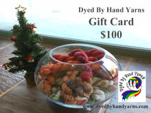 Load image into Gallery viewer, In the foreground is a round glass bowl full of multi-coloured mini skeins; behind this to the left is a decorated mini Christmas tree. This stands on a tan brown stone tile floor. There is dark grey writing in the top right hand corner that says Dyed By Hand Yarns Gift Card $100. In the bottom right hand corner is a multi-coloured logo. Under this in dark grey is a web address
