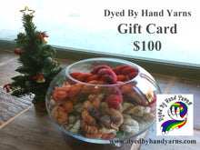 Load image into Gallery viewer, In the foreground is a round glass bowl full of multi-coloured mini skeins; behind this to the left is a decorated mini Christmas tree. This stands on a tan brown stone tile floor. There is dark grey writing in the top right hand corner that says Dyed By Hand Yarns Gift Card $100. In the bottom right hand corner is a multi-coloured logo. Under this in dark grey is a web address