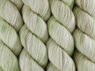 A close up of lightly variegated white, light cocoa brown and pale green coloured skeins of superwash merino and nylon 4ply fingering sock yarn (Flannel Flower on Tough Stocking)