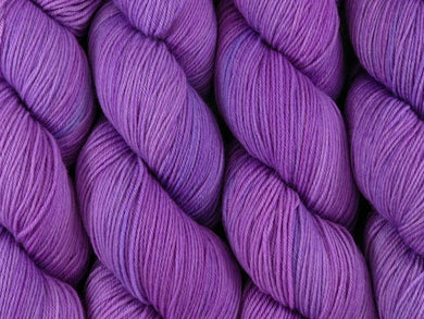 A close up of semi-solid mauve-pink coloured skeins of superwash merino and nylon 4ply fingering sock yarn (Fringe Lily on Tough Stocking)