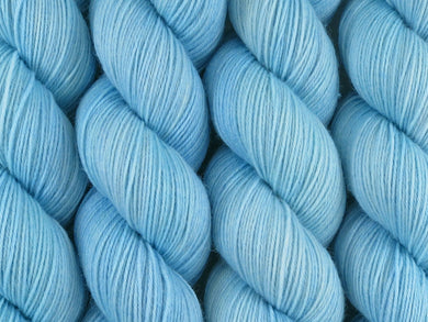 A close up of semi-solid light clear blue leaning towards aqua coloured skeins of superwash merino and nylon 4ply fingering sock yarn (Little Boy Blue on Tough Stocking)
