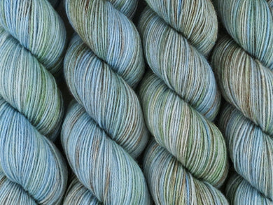 A close up of variegated blue, aqua and brown with hints of kelly green coloured skeins of superwash merino and nylon 4ply fingering sock yarn (Rockpool on Tough Stocking)