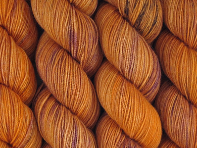 A close up of variegated rusty orange, tan and maroon with black speckles coloured skeins of superwash merino and nylon 4ply fingering sock yarn (Rusty Holden Ute on Tough Stocking)
