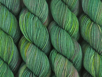 A close up of variegated light grey-green with hints of pink, sulphur yellow and deep jade green coloured skeins of superwash merino and nylon 4ply fingering sock yarn (Samphire on Tough Stocking)