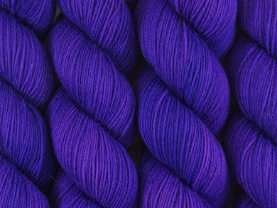 A close up of semi-solid deep purple coloured skeins of superwash merino and nylon 4ply fingering sock yarn (Snozzberries on Tough Stocking)