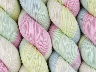 A close up of variegated space-dyed pastel white, pink, yellow, blue and green coloured skeins of superwash merino and nylon 4ply fingering sock yarn (Sugared Almonds on Tough Stocking)