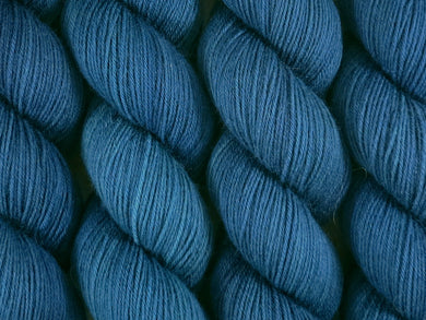 A close up of deep semi-solid blue green, teal and navy with hints of emerald green coloured skeins of superwash merino and nylon 4ply fingering sock yarn (The Kraken Wakes on Tough Stocking)