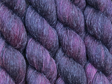 A close up of variegated black, maroon, plum and wine coloured skeins of non-superwash baby alpaca, silk and linen 4ply fingering weight yarn (Blackened Rose on Spinifex)