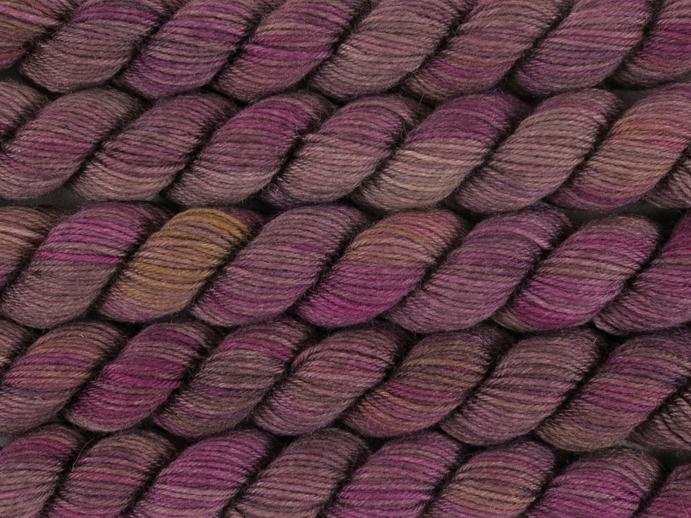 A close up of variegated brown, beige-grey, pink, purple and yellow mini skeins of superwash merino and nylon 4ply fingering sock yarn arranged horizontally (Boronia on Tough Stocking Mini)