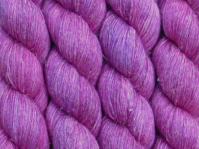 A close up of bright semi-solid cool pink with hints of mauve pink, cerise, magenta and maroon coloured skeins of non-superwash baby alpaca, silk and linen 4ply fingering weight yarn (Lilly Pilly on Spinifex)