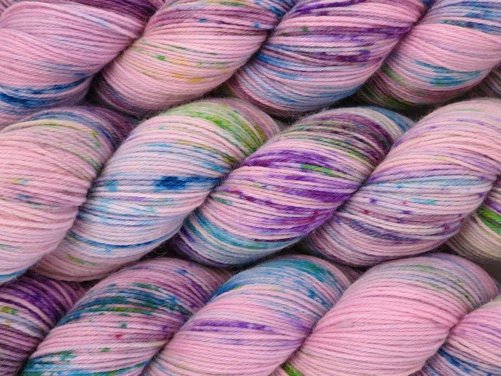 A close up of pale pink with speckles of purple, blue and green coloured skeins of superwash merino and nylon 4ply fingering sock yarn (One Hit Wonder 3 on Tough Stocking)