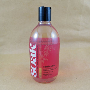 One large bottle of Soak rinse-free laundry liquid with a dark pink label, on a tan background (Celebration scent)