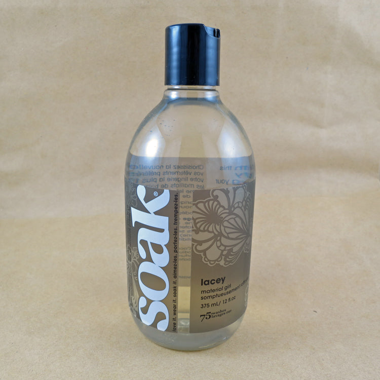 One large bottle of Soak rinse-free laundry liquid with a grey label, on a tan background (Lacey scent)
