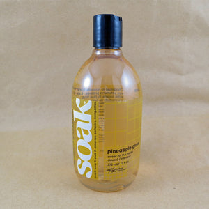 One large bottle of Soak rinse-free laundry liquid with a yellow label, on a tan background (Pineapple Grove scent)