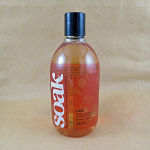 One large bottle of Soak rinse-free laundry liquid with an orange label, on a tan background (Yuzu scent)