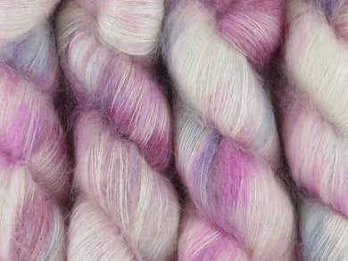 A close up of variegated cool pink and white with hints of grey, silver and maroon coloured skeins of superfine kid mohair and silk 2ply lace yarn (Steel Magnolia on Kid Glove Lace)