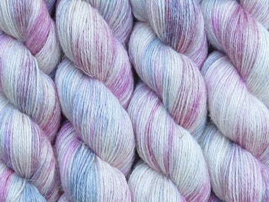 A close up of variegated cool pink and white with hints of grey, silver and maroon coloured skeins of non-superwash baby alpaca, silk and linen 4ply fingering weight yarn (Steel Magnolia on Spinifex)