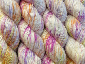 A close up of white with bright speckles of pink, purple, orange and yellow coloured skeins of non-superwash baby alpaca, silk and linen 4ply fingering weight yarn (Titillation on Spinifex)