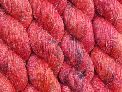 A close up of variegated bright orange, red and fuchsia with black speckles coloured skeins of non-superwash baby alpaca, silk and linen 4ply fingering weight yarn (Total Fire Ban on Spinifex)