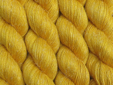 A close up of semi-solid deep golden yellow coloured skeins of non-superwash baby alpaca, silk and linen 4ply fingering weight yarn (Turmeric on Spinifex)