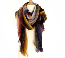 Load image into Gallery viewer, A knitted wrap with short fringe at the ends made from twenty five mini skeins arranged in gradient colour order from purples through greens to creams and pinks through browns to yellows looped around the neck of a white dress mannequin on a white background (Adventuring Wrap by Ambah O&#39;Brien)
