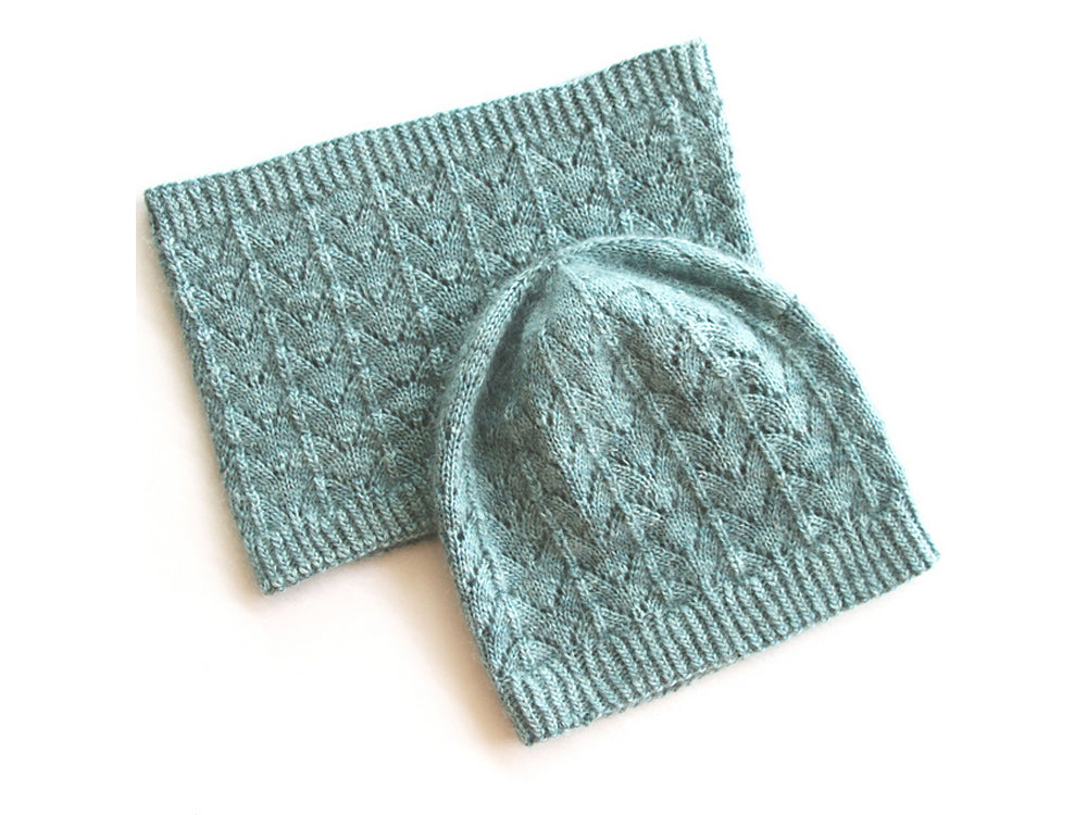 A pale blue-green fishtail lace beanie sits partly on top of a matching lace cowl, on a white background.
