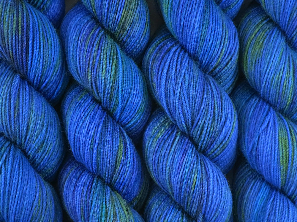 A close up of variegated bright blue, deep violet and emerald green coloured skeins of superwash merino and nylon 4ply fingering sock yarn (Blue Quandong on Tough Stocking)