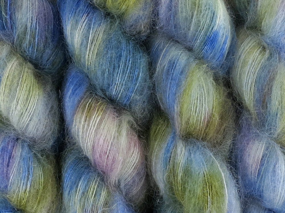 A close up of variegated cobalt blue, white, moss green and violet coloured skeins of superfine kid mohair and silk 2ply lace yarn (Blue Swimmer Crab on Kid Glove Lace)