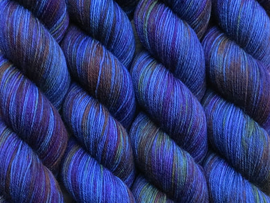 A close up of variegated deep denim blue, deep pink, orange and green coloured skeins of superwash merino and nylon 4ply fingering sock yarn (Breast Friends Forever on Tough Stocking)