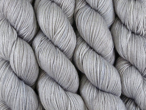A close up of semi-solid grey with hints of silver, graphite and steel blue coloured skeins of superwash merino and silk 4ply fingering sock yarn (Fog Bound on Silk Stocking)