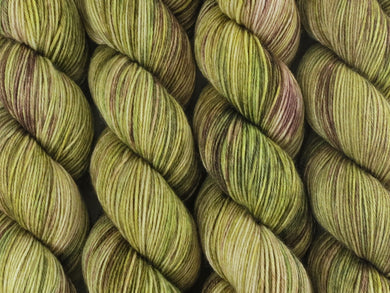 A close up of variegated khaki and forest greens, ecru and brown coloured skeins of superwash merino and nylon 4ply fingering sock yarn (Gone Bush on Tough Stocking)