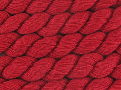 A close up of semi-solid red with hints of maroon and crimson mini skeins of superwash merino and nylon 4ply fingering sock yarn arranged horizontally (Japonica on Tough Stocking Mini)