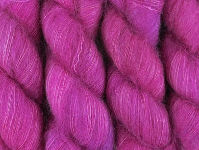 A close up of bright semi-solid cool pink with hints of mauve pink, cerise, magenta and maroon coloured skeins of superfine kid mohair and silk 2ply lace yarn (Lilly Pilly on Kid Glove Lace)