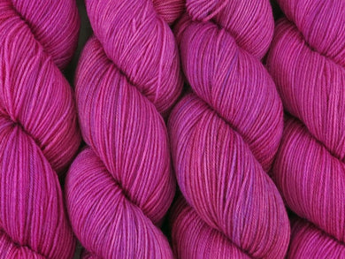 A close up of bright semi-solid cool pink with hints of mauve pink, cerise, magenta and maroon coloured skeins of superwash merino and nylon 4ply fingering sock yarn (Lilly Pilly on Tough Stocking)