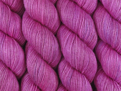 A close up of bright semi-solid cool pink with hints of mauve pink, cerise, magenta and maroon coloured skeins of superwash merino and silk 4ply fingering sock yarn (Lilly Pilly on Silk Stocking)