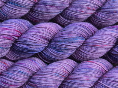 A close up of mauve with speckles of blue, pink and charcoal coloured skeins of superwash merino and nylon 4ply fingering sock yarn (One Hit Wonder 1 on Tough Stocking)