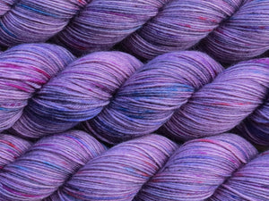 A close up of mauve with speckles of blue, pink and charcoal coloured skeins of superwash merino and nylon 4ply fingering sock yarn (One Hit Wonder 1 on Tough Stocking)