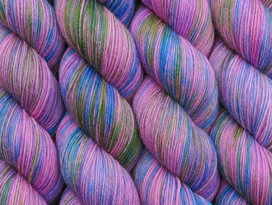 A close up of variegated pink with splashes of mid-blue, mauve and green coloured skeins of superwash merino and nylon 4ply fingering sock yarn (Pinkapalooza on Tough Stocking)