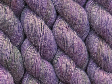 A close up of variegated purple, violet and green with hints of hot pink and beige coloured skeins of non-superwash baby alpaca, silk and linen 4ply fingering weight yarn (Purple Sea Urchin on Spinifex)