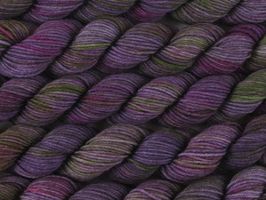 A close up of variegated purple, violet and green with hints of hot pink and beige mini skeins of superwash merino and nylon 4ply fingering sock yarn arranged horizontally (Purple Sea Urchin on Tough Stocking Mini)