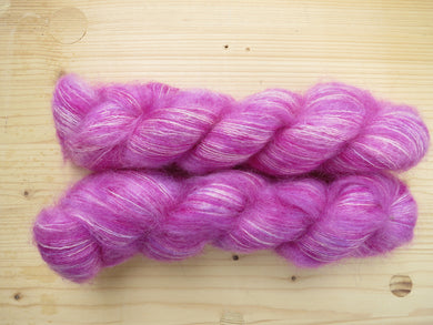 A close up of variegated deep pink, white and bright pink with hints of purple coloured skeins of superfine kid mohair and silk 2ply lace yarn (Raspberry Ripple on Kid Glove Lace)