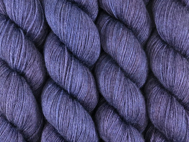 A close up of semi-solid dark blue, midnight blue, deep red-purple and maroon coloured skeins of superwash merino and silk 4ply fingering sock yarn (Round Midnight on Silk Stocking)