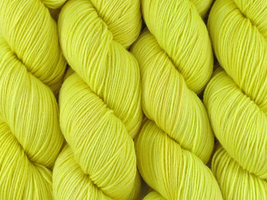 A close up of semi-solid light bright lemon yellow with hints of neon yellow and gold coloured skeins of superwash merino and nylon 4ply fingering sock yarn (Sherbet Lemon on Tough Stocking)