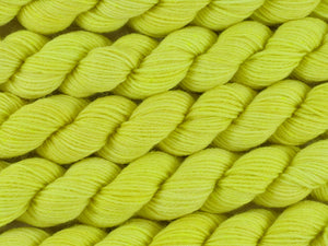 A close up of semi-solid light bright lemon yellow with hints of neon yellow and gold mini skeins of superwash merino and nylon 4ply fingering sock yarn arranged horizontally (Sherbet Lemon on Tough Stocking Mini)