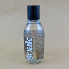 Load image into Gallery viewer, One small bottle of Soak rinse-free laundry liquid with a grey label, on a tan background (Lacey scent)
