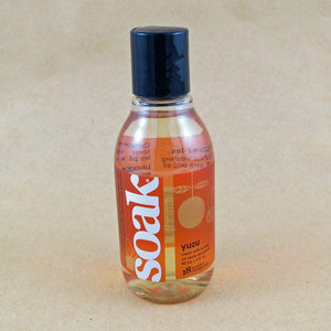 One small bottle of Soak rinse-free laundry liquid with an orange label, on a tan background (Yuzu scent)